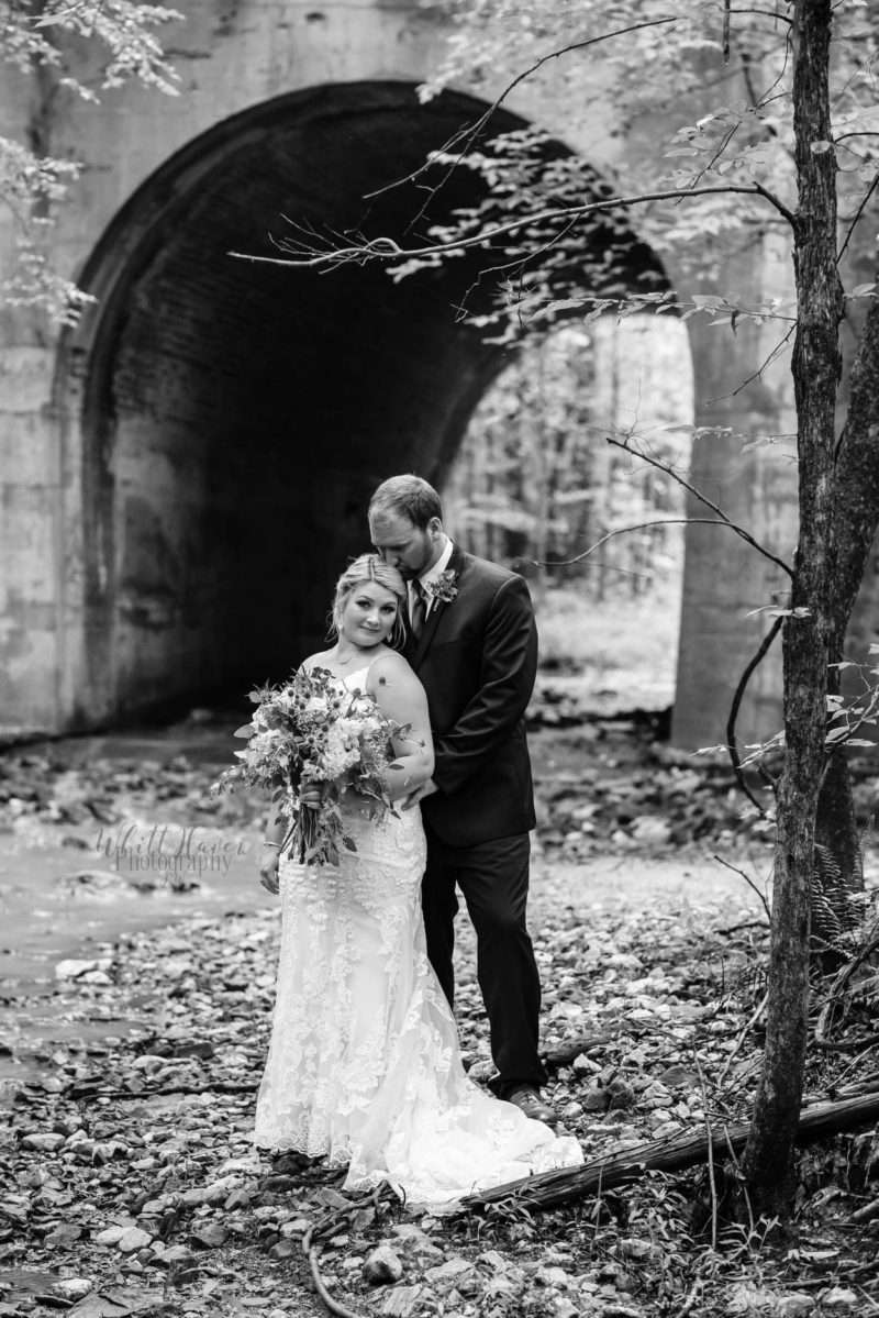 A bride and groom embracing among the vines